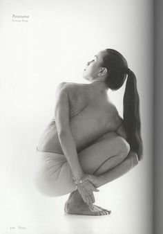 a black and white photo of a woman with long hair sitting on the ground in yoga pose