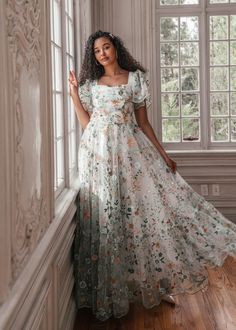 a woman in a long dress leaning against a wall