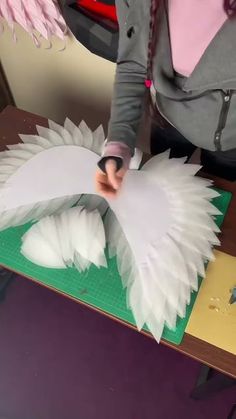 a woman is cutting paper with scissors on a table