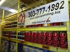 there are many red and white buckets on the shelves in this store that is full of paint