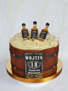 a birthday cake made to look like an old barrel with three bottles of whiskey in it