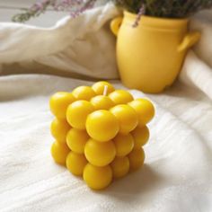 a bunch of yellow beads sitting on top of a white blanket next to a potted plant