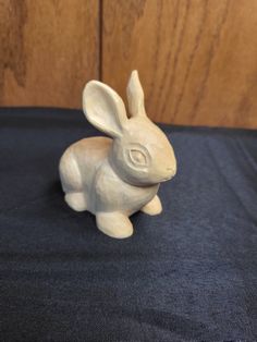 a white ceramic rabbit sitting on top of a blue cloth