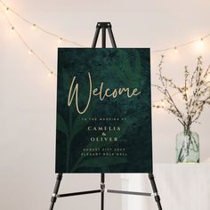 an easel with a welcome sign on it in front of a string of lights