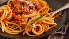 a plate of spaghetti with meat sauce and parmesan cheese on top, ready to be eaten