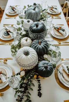 the table is set with black and white pumpkins, greenery and candlesticks