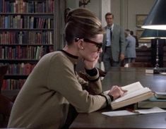 a woman sitting at a table in front of a book