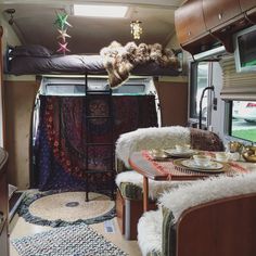 the inside of a camper with a table and chairs, rugs on the floor