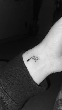 a black and white photo of a person's hand with a small scissors tattoo on it