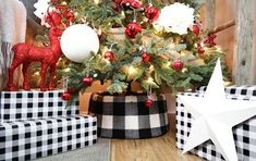 a christmas tree decorated with red, white and black ornaments sits in front of presents