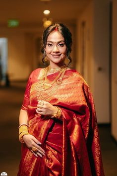 a woman in a red and gold sari is posing for the camera with her hands on her hips