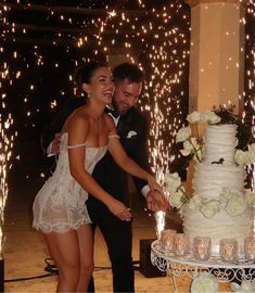 a newly married couple cutting their wedding cake with sparklers in the air behind them