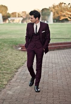 a man in a suit and tie walking down a brick path with his hand in his pocket