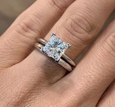 a woman's engagement ring with a princess cut diamond in the center and two matching bands