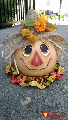 a pumpkin with a scarecrow's hat and leaves on it sitting on the ground