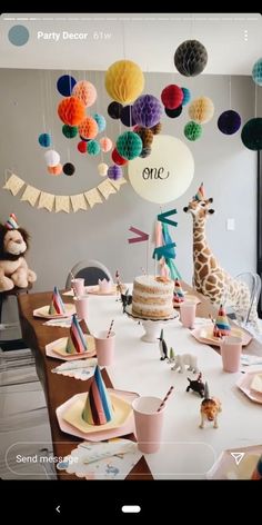 a birthday party with giraffes, balloons and other decorations on the table