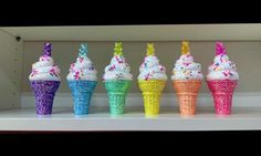 an assortment of ice cream cones with sprinkles on them in a display case