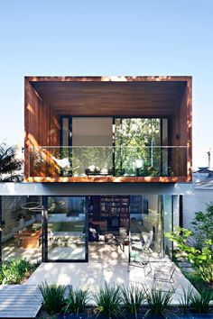 the house is surrounded by trees and plants, with glass doors open to let in natural light