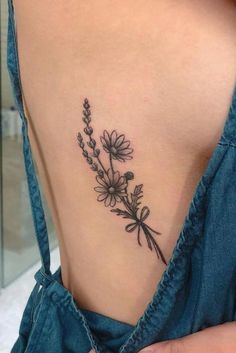 the back of a woman's neck with flowers on her left side and an arrow tattoo