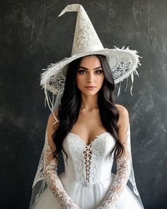 a woman in a white dress and hat with long hair posing for the camera wearing a veil