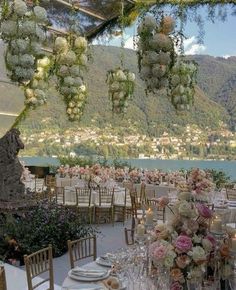 an outdoor dining area with tables, chairs and flowers hanging from the ceiling above it