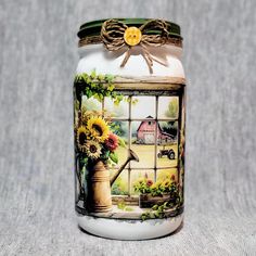 a painted jar sitting on top of a table next to a window with sunflowers