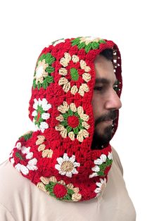 a man wearing a red crocheted scarf with flowers on it's hood