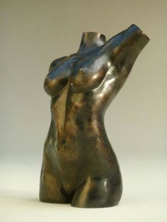 a bronze colored sculpture of a woman's torso with her hands in the air