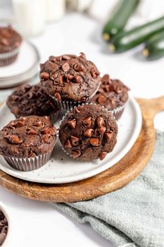 chocolate muffins on a white plate with other cupcakes in the background