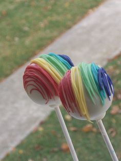 two lollipops with different colors on them sitting in front of a sidewalk