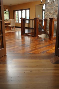 an open living room with wood flooring and railings in the center, looking into the dining area