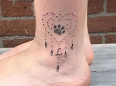 a dog's paw and heart tattoo on the side of a foot with rain drops