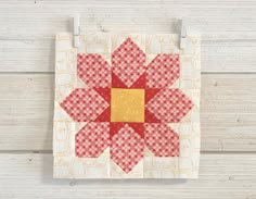 a red and white quilt with a flower on the front, hanging from a hook