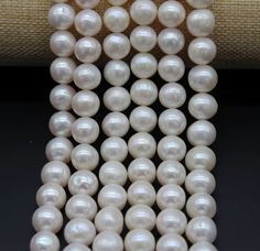 three strands of white pearls on a black surface