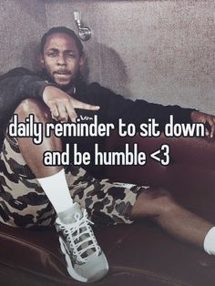 a man sitting on top of a couch next to a wall with the words daily reminder to sit down and be humble > 3