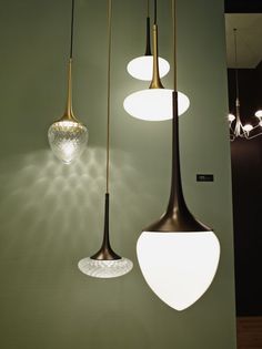 three different lights hanging from the ceiling in a room with green walls and flooring