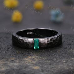 a black ring with a green stone in the middle