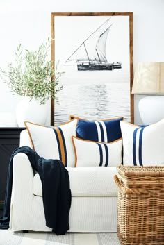 a living room with a white couch and blue striped pillows on the back of it