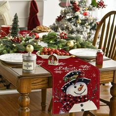 a dining room table with christmas decorations and plates on it, including a snowman placemat