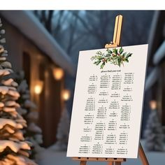 an easel with a christmas program on it in front of a snowy tree and house