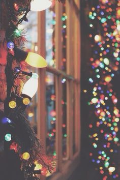 a christmas tree with lights on it in front of a window and a decorated door