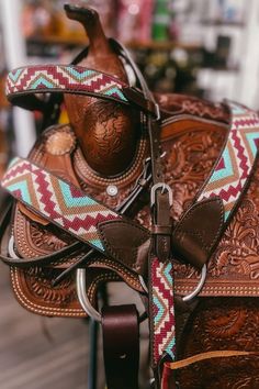 a saddle that is sitting on top of a wooden stand with a cowgirl's hat on it