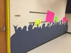 a classroom door decorated with post it notes and people silhouettes on the wall,