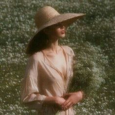 a woman wearing a hat and dress standing in a field