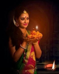 a beautiful woman holding a plate of food in front of a lit candle on a table