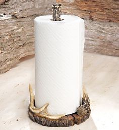 a white toilet paper holder with deer antlers on the bottom and a wooden base