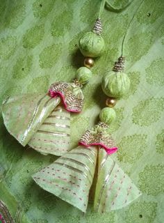 three green ornaments are hanging on a table cloth with beads and pearls in the shape of bells