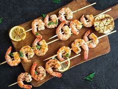 shrimp skewers with lemon wedges on a wooden cutting board