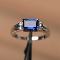 It is a lab sapphire ring. The main stone is 6mm*8mm emerald cut, weight about 1.70 carats. The basic metal is sterling silver and plated with rhodium. To change the metal to a solid gold (white/rose) or platinum is also available, please ask for a quotation if you want. You can also go to my shop Home for more elegant rings: https://www.etsy.com/shop/godjewelry?ref=hdr_shop_menu Sapphire is the birthstone of September. More sapphire rings: https://www.etsy.com/shop/godjewelry?ref=listing-shop2- Blue Gemstone Engagement Rings, Emerald Cut Sapphire Ring, September Birthstone Rings, Emerald Cut Diamond Ring, Blue Gemstone Rings, Sapphire Solitaire, Pink Sapphire Ring, Emerald Engagement Ring Cut, Sapphire Engagement Ring Blue