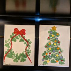 two handmade christmas cards on display in front of a black wall with green and red decorations